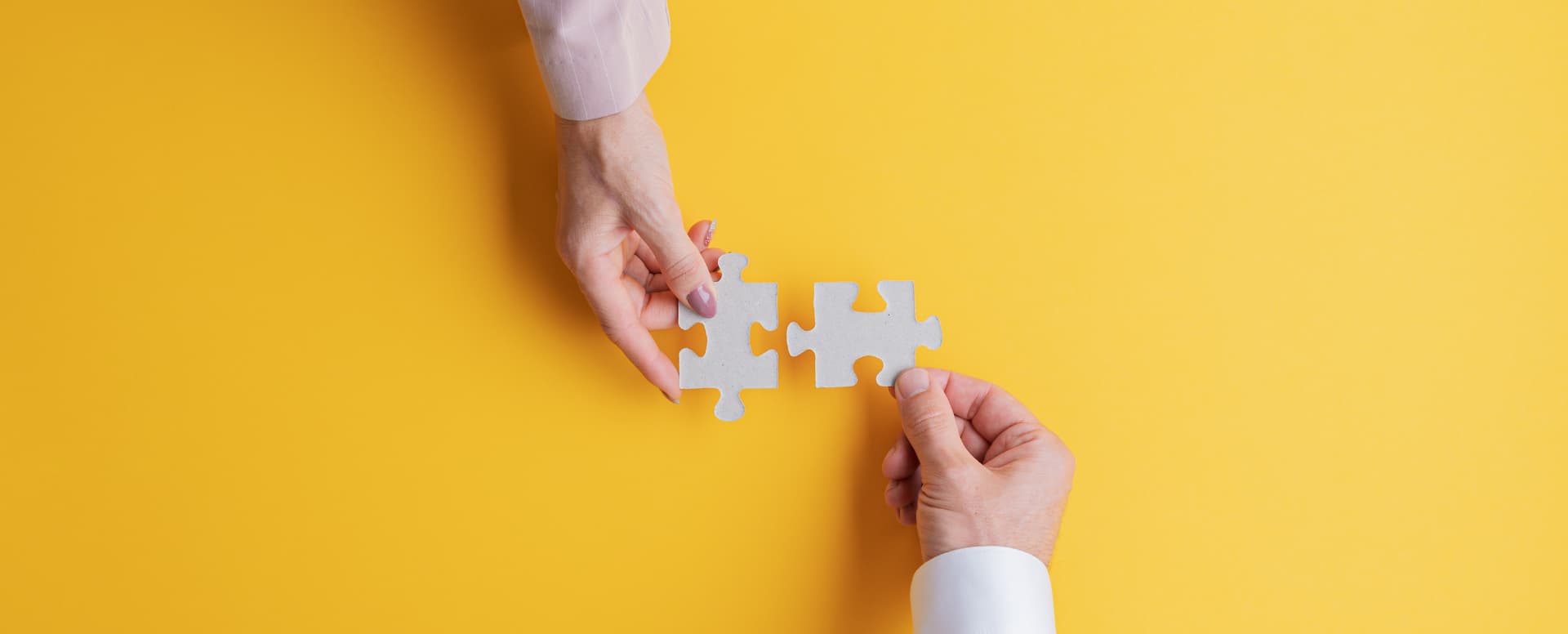 two hands holding two puzzle pieces